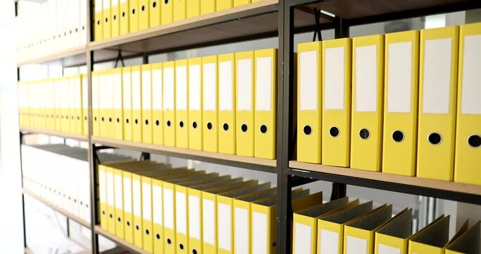 Closeup of bright identical yellow folders on shelf in office
