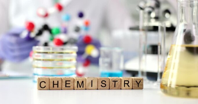 Word chemistry on laboratory table with microscope, laboratory glassware and molecular structure
