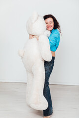 a woman stands with a large soft teddy bear toy