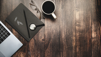 Naklejka premium Wooden office desk with laptop, notebook and pen on dark background. Top view. Flat lay. Business concept.