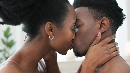 Couple kiss, bedroom sex and love on bed in house, erotic sexual energy in marriage and nude people being sexual together in home. Happy African man and woman kissing with passion in apartment © Nina/peopleimages.com