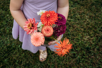 Person holding bouquet of red zinnias at flower field