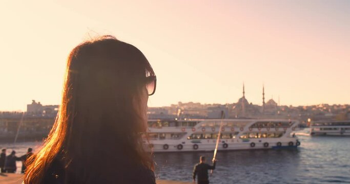 Woman eating simit, turkish bagel with Istanbul city view at sunrise light