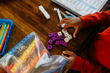 Black child’s hand counting with home school supplies