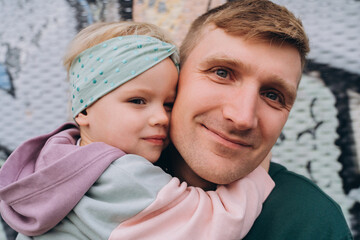 Close-up portrait of father and daughter in hoodies, pastel colors