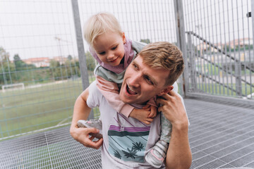 Dad and baby daughter have fun near the football field stadium