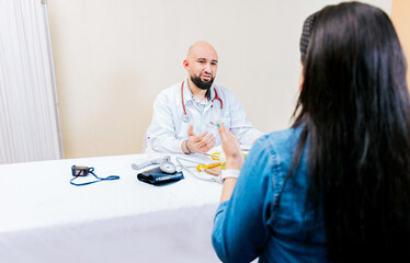 Fototapeta premium Back view of a female patient talking to the nutritionist. Smiling nutritionist explaining to a female patient, Nutritionist man talking to woman patient in office