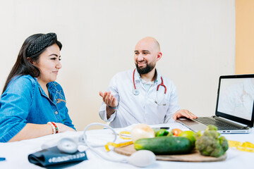 Smiling nutritionist explaining to a female patient, Nutritionist man talking to woman patient in office. Back view of a female patient talking to the nutritionist