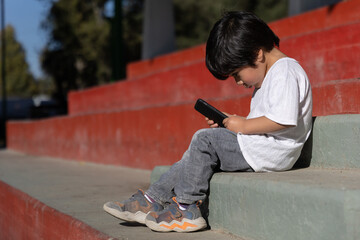 Mexican kid playing with Mobile Devices outdoors