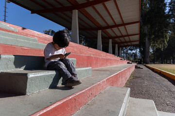 Mexican kid playing with Mobile Devices outdoors