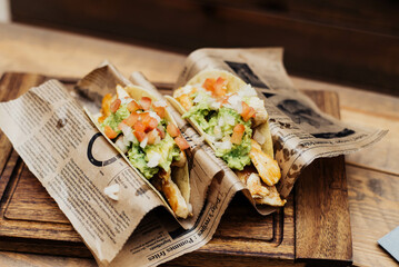 Chicken tacos with guacamole and vegetables on wooden table