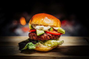 Burger on a wooden table in front of a fireplace.