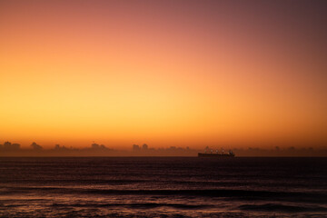 golden hour sunrise over the ocean with a ship silhouette