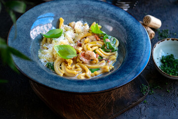 Cooking casarecce pasta with shrimp, basil and cream sauce in a blue plate. Italian dish casarecce seafood