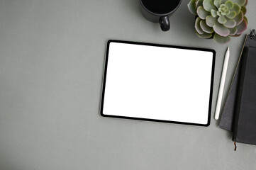 Top view of workspace with tablet mockup, stylus pen, and accessories on grey background.