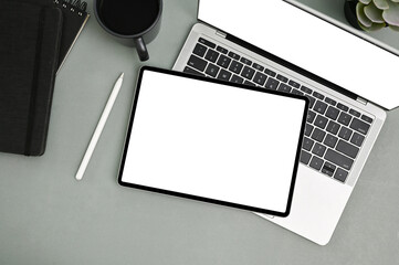Tablet mockup on laptop keyboard, stylus pen, coffee cup and notepad on grey background