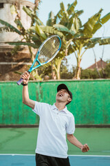 Excited men's singles athlete shouting and lifting racket on tennis court