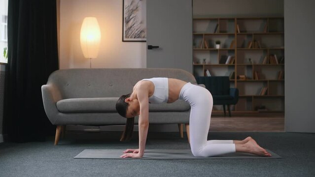 Young woman with slim body type doing yoga at home.
