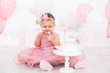 cute little child girl eating birthday cake and celebrating her first birthday