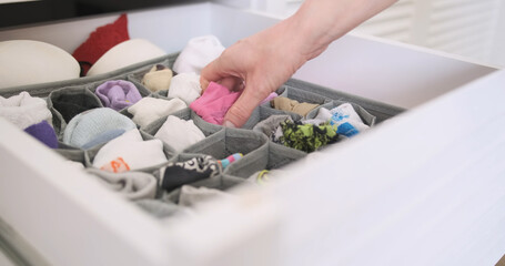 Woman's hand opens drawer with neatly folded socks. Selects pink socks and closes the drawer. Side view