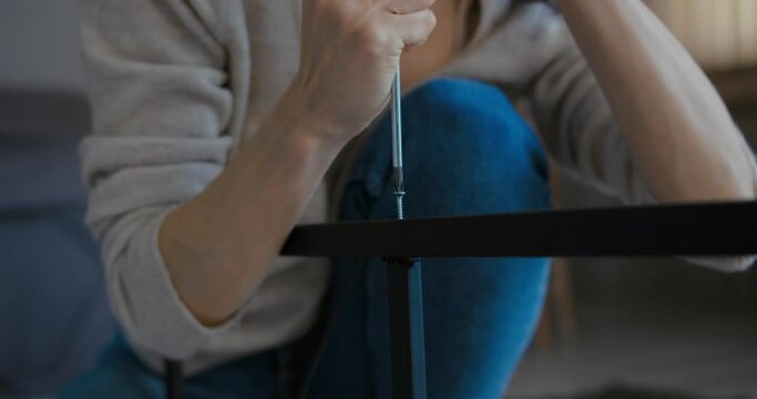 Woman assembling furniture on the floor at home, close-up shot
