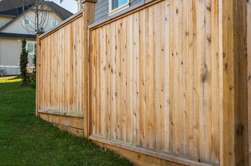 Fototapeta na wymiar Nice wooden fence around house. Wooden fence with green lawn. Street photo