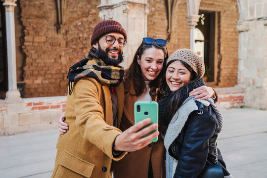 Group of smiling turists friends taking a selfie portrait with a cellphone together to share in the social media app. Young people doing a photo on a travel or vacation trip. High quality photo