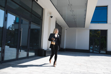 Fototapeta na wymiar A business lady in a stylish suit walks near the business center