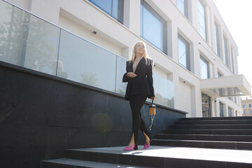 Fototapeta na wymiar A young woman in a stylish black suit walks down the street