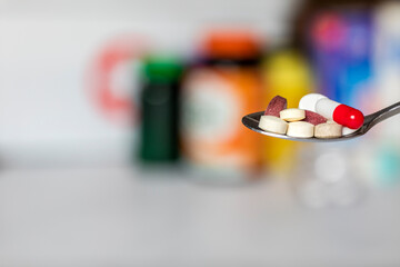 Assorted pharmaceutical medicine pills, tablets and capsules on spoon, pharmacy background with copy space, illness,drugs,pill treatment health concept