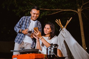 guy in plaid shirt standing with a cup of coffee at his hand and looking at the woman's phone