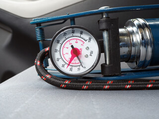Close up of foot pump. barometer on the car seat