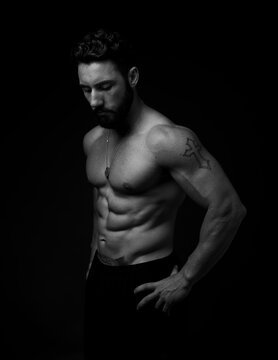 A physically fit man pictured on a black background.