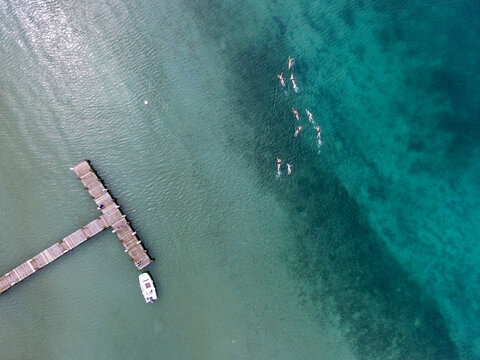 An Aerial View Of A Jetty With A Motor Boat With A Women Swimming In The Ocean