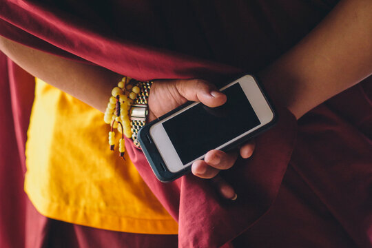 A smartphone is held in the hands of a Buddhist monk in Nepal.