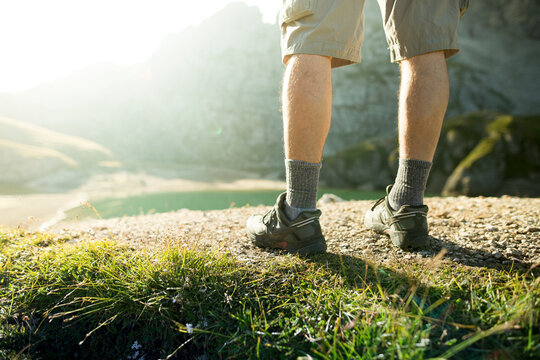 A man's hiking legs stop over a lake in the Civetta region of the Dolomites, Italy.