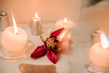 Spa center. Details decor in spa salon. Gua sha tool. Candles, and orchid flowers on table. Facial massage for lifting, face therapy. Skincare concept. Cosmetology, body massage, spa procedure.
