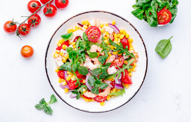 Delicious shrimp salad with sweet corn, cherry tomatoes, lamb lettuce and red onion on white table background. Top view