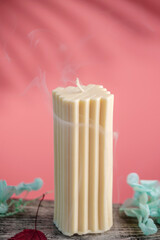 Rectangular handmade candle on a wooden table and the pink background