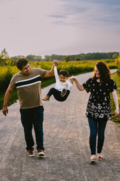 Mom and hispanic Dad play with son on hike outside