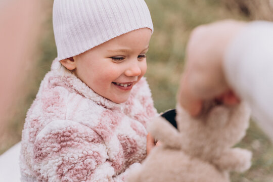 Toothless baby girl in the park laughs and drinks tea from thermos