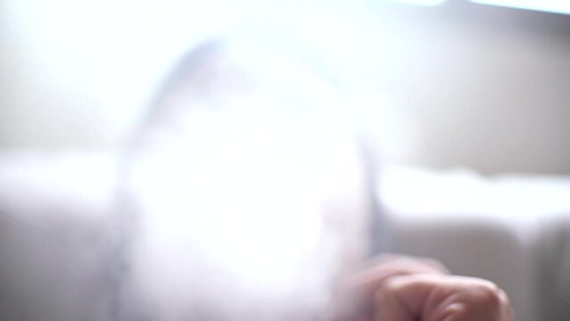 Woman smoking vaper or e-cigarettes at home close-up view focusing on vaper tip and smoke with narrow depth of field. Unidentified person.