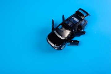 Black toy car with opened doors on blue backgroud. Concept buying new car.