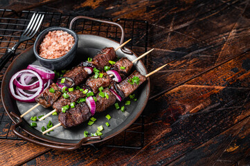 Kebabs grilled meat skewers, shish kebab with onion and herbs, grilled beef meat. Wooden background. Top view. Copy space