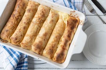 Filled pancakes with sour cream lemon filling in a baking dish
