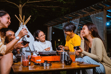 a woman with eye glasses laughing while looking at the guy in yellow t shirt that sitting next to the woman in cardigan