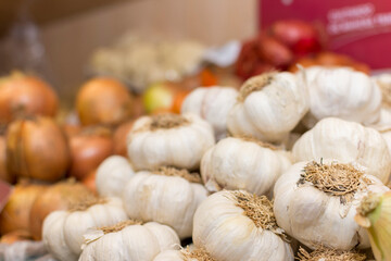 A pile of garlic on a table and others vegetables