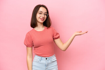 Young Ukrainian woman isolated on pink background extending hands to the side for inviting to come