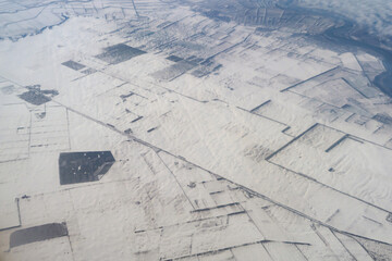 Wing of aerial view of an airplane jet flying above clouds from the window in traveling and transportation concept. White snow mountain in winter season. Nature landscape background.