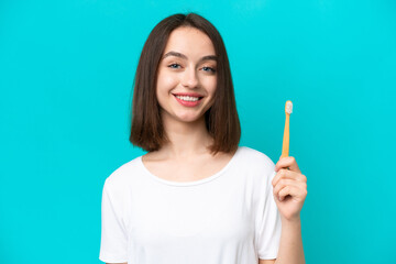 Young Ukrainian woman brushing teeth isolated on blue background smiling a lot